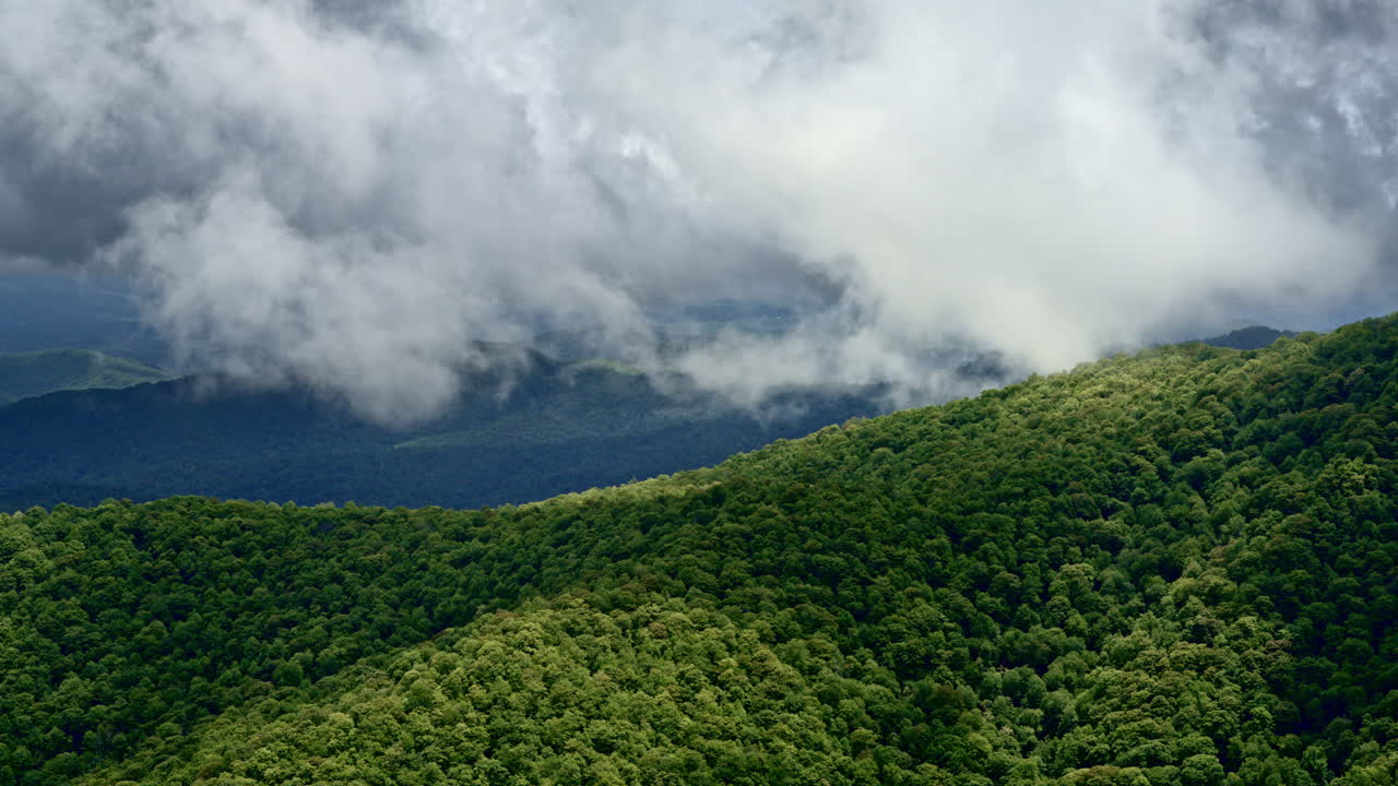 Soaring aerial shot of Smoky Mountains draped in fog and brushed by rainfall