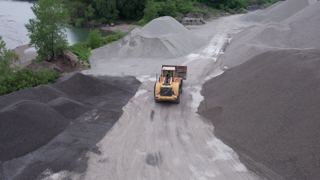 자갈 구덩이에서 자갈 더미 사이에서 작업하고 운전하는 로더