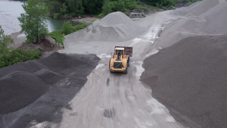 Lader-Arbeitet-Und-Fährt-Zwischen-Kieshaufen-In-Kiesgrube