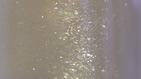 보드카에 떠다니는 반이는 빛의 클로즈업, 물에 이는 다채로운 금색 페인트, 물 에서 회전하는 잉크, 실키 잉크의 구름, 매크로 뷰