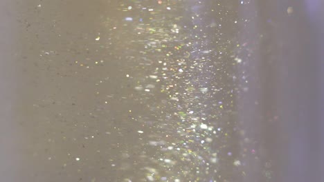 close-up of glitter floating in vodka. colorful gold paint mixing in water. ink swirling underwater. cloud of silky ink. macro view