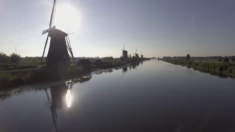 A-drone-shot-panning-forward,-around-Dutch-Windmills-during-sunrise