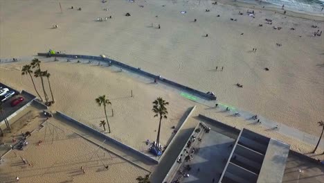 venice beach california disparo de drones avanzando panorámico en frente de la playa sobre canchas de baloncesto con arena y agua