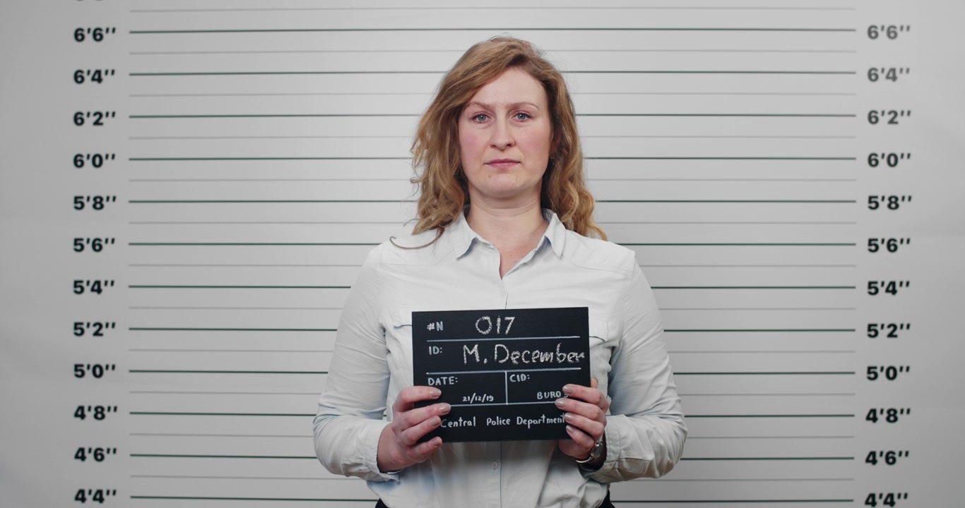 Donna in posa per la foto segnaletica della polizia mentre tiene in mano il cartello identificativo