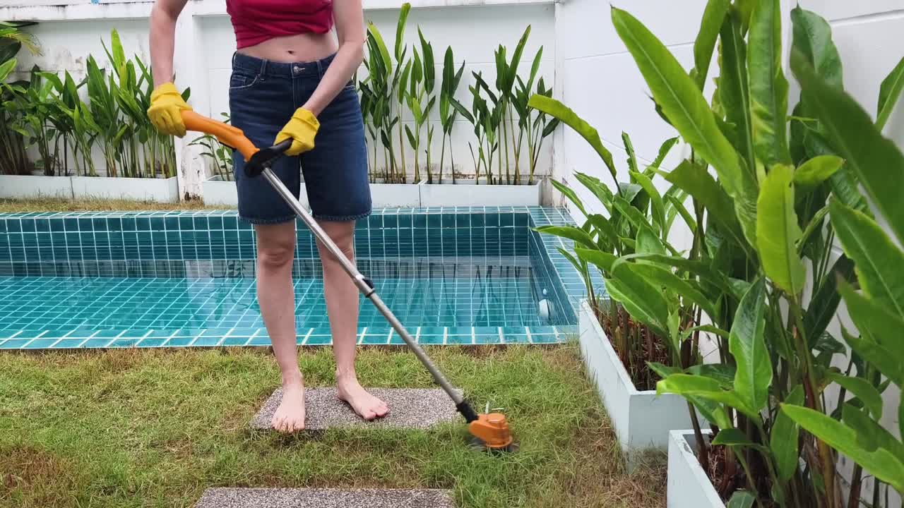 Woman Trimming Lawn with String Trimmer in Backyard
