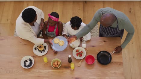 overhead view of african american grandparents and grandchildren preparing pancakes in the kitchen