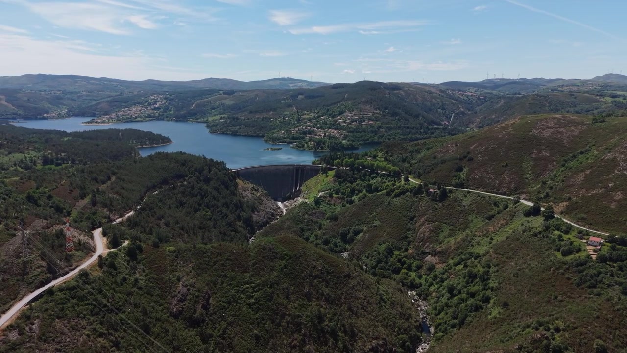Aerea - Ampia vista della valle della diga del bacino di Ermal con strada tortuosa, colline boscose e villaggi a Braga, Portogallo.