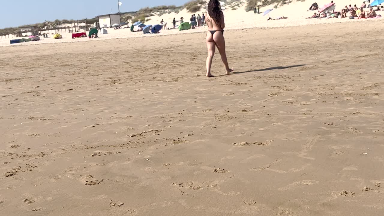 비키니를 입은 건강하고 매력적인 여성은 신선한 바다에서 모래 해변으로 우아하게 전환하여 자신감을 발산하고  ⁇ 은 날을 최대한 즐기고 있습니다.