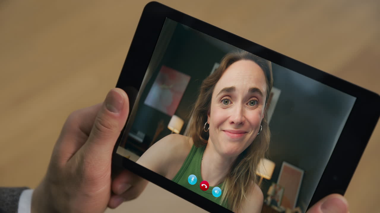 Primo piano di una ragazza sorridente che flirta durante una videochiamata su un tablet in casa. Appuntamento tramite webcam