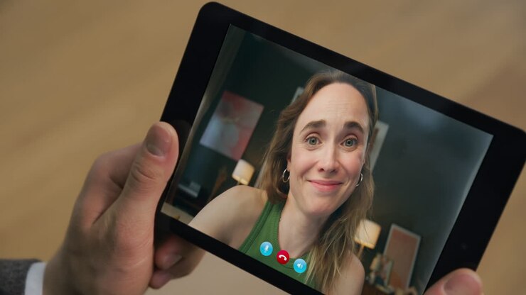 Primo piano di una ragazza sorridente che flirta durante una videochiamata su un tablet in casa. Appuntamento tramite webcam