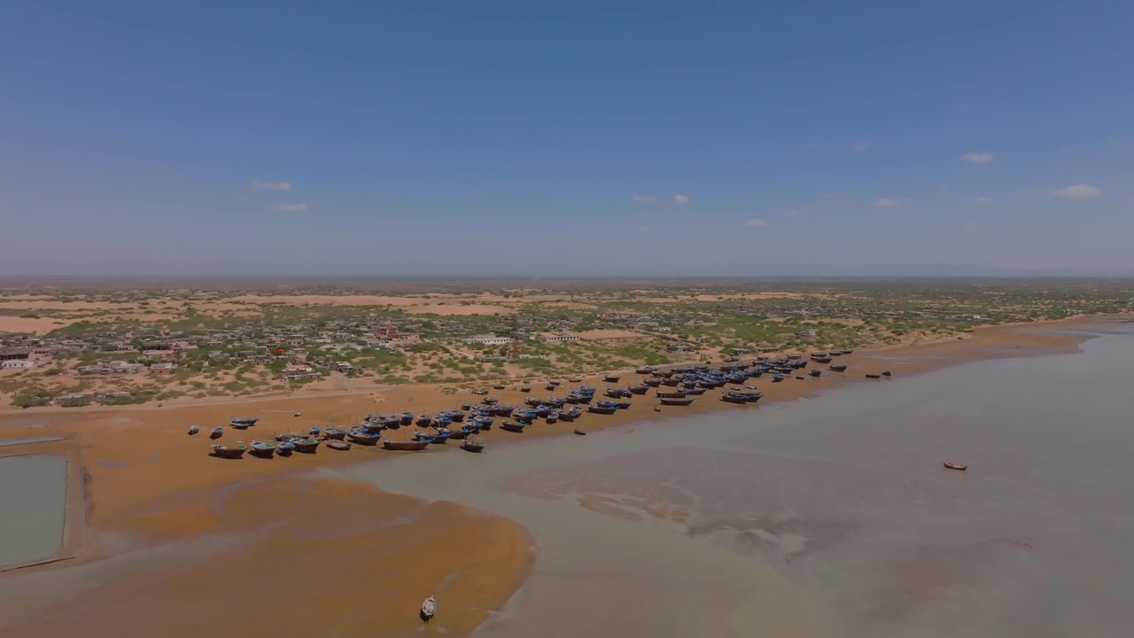 Luftfoto som viser mange fiskebåter som hviler på store mudderflater ved Damb Beach i Balochistan. Denne scenen fanger essensen av kystlivet og tradisjonelle fiskemetoder