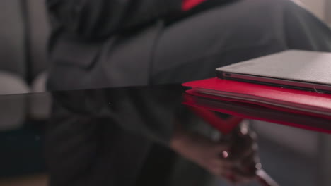 close-up of red smartphone on top of red notebooks and laptop on glossy desk in office setting. focus on work tools, productivity, and organized corporate workspace