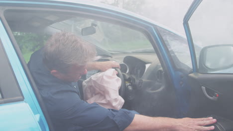 motorista herido en un accidente automovilístico con el airbag desplegado saliendo del vehículo