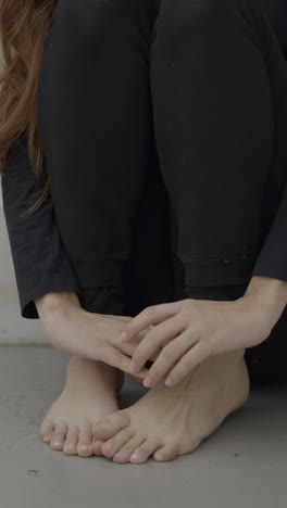 close-up of a person sitting on the floor, showcasing feet and hands