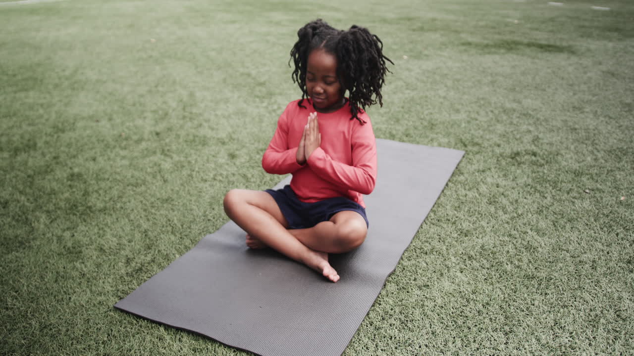 Young girl sitting on yoga mat outdoors, focusing on mindfulness practice, copy space