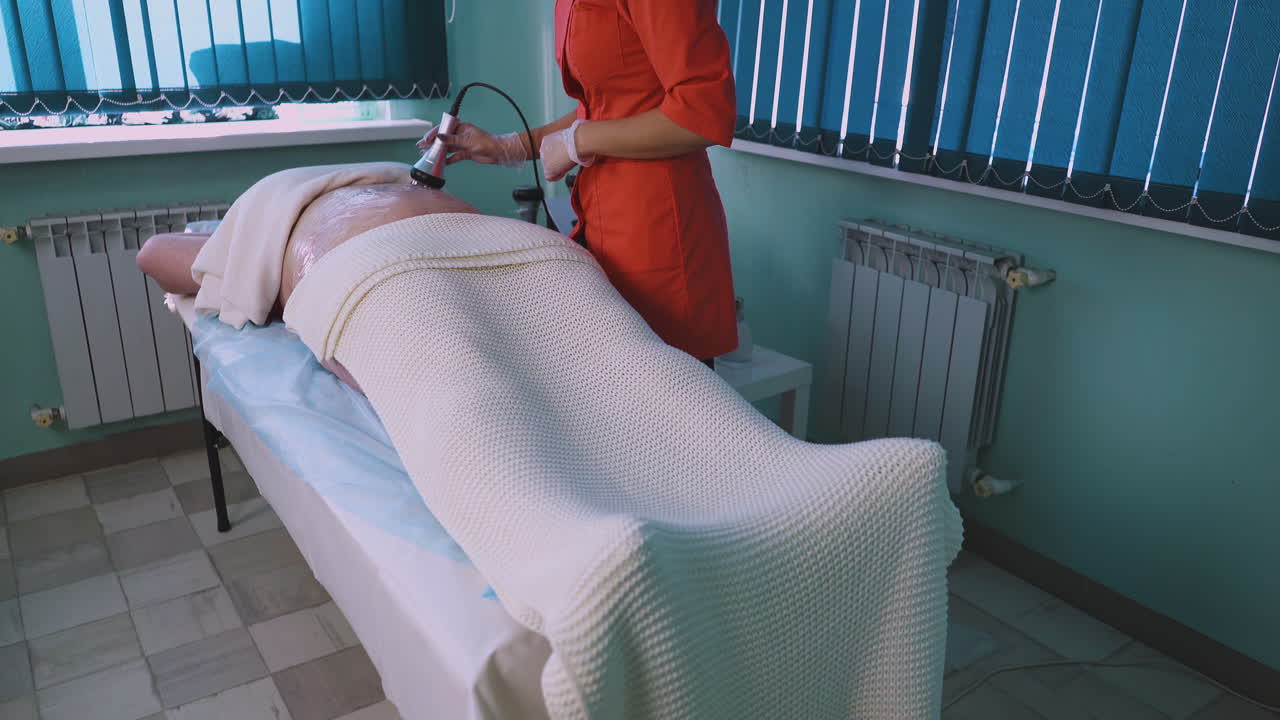 미용학자는 클리닉에서 플러스 사이즈 여성에게 바이브로 마사지를 합니다.