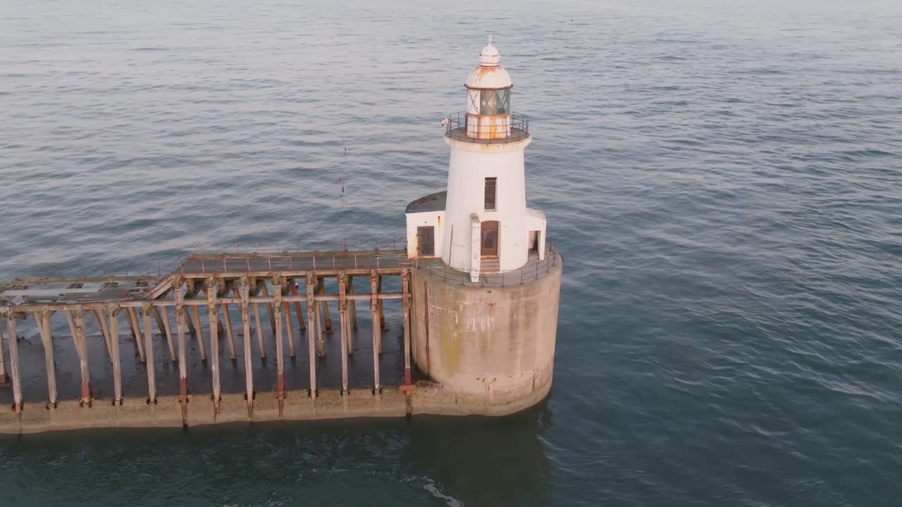 Rusted lighthouse and long jetty in Northumberland surrounded by North Sea