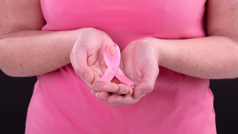 Video-Des-Mittelteils-Einer-Kaukasischen-Frau,-Die-Ein-Rosafarbenes-Krebsbewusstseinsband-Hält