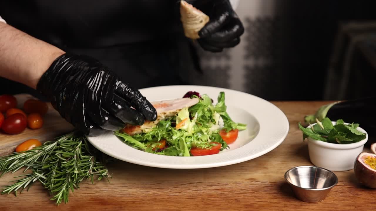 Chef Plating a Gourmet Salad with Cooked Meat in a Restaurant Kitchen