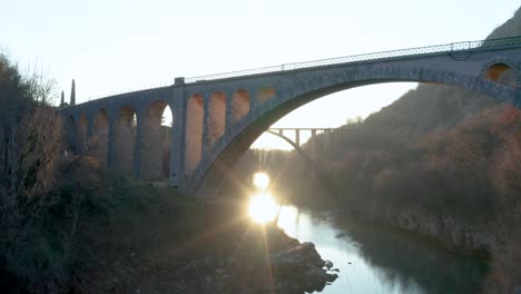 Aerial---Large-arched-stone-bridge-side-view-in-sunset,-Solkan-Slovenia