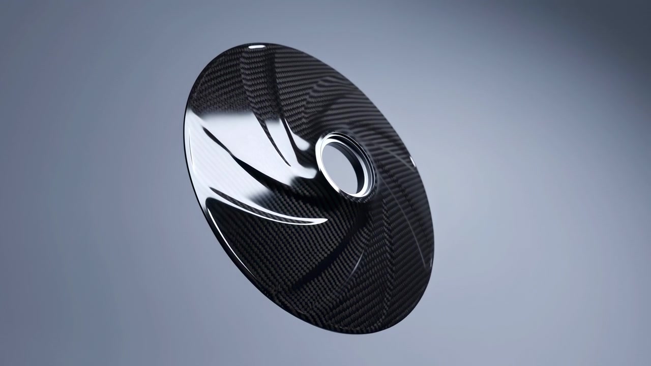 Shifting highlights move across a dark textured ring as it turns through changing angles, keeping its round opening visible while reflective ridges stand out in neutral studio lighting.