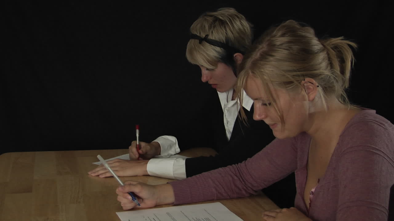 las mujeres se sientan en una mesa y completan el papeleo