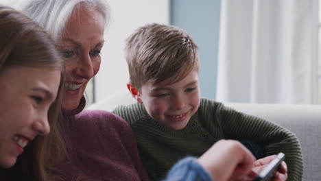 Großmutter-Spielt-Zu-Hause-Videospiel-Mit-Enkelkindern-Auf-Dem-Handy