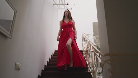 pretty woman glides down staircase. young woman ensures radiant presence and leaves lasting impression in luxurious residence. woman trail of enchantment