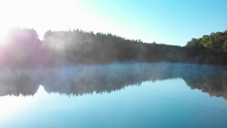 Sunrise-over-forest-in-front-of-foggy-lake---panning-shot-1