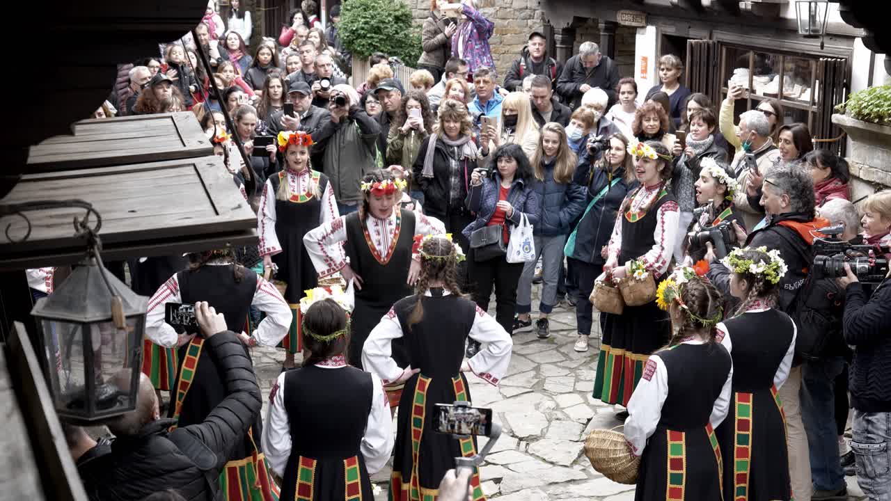 Pretty Bulgarian girls in colourful traditional dress perform Easter time ritual dance in front of crowds