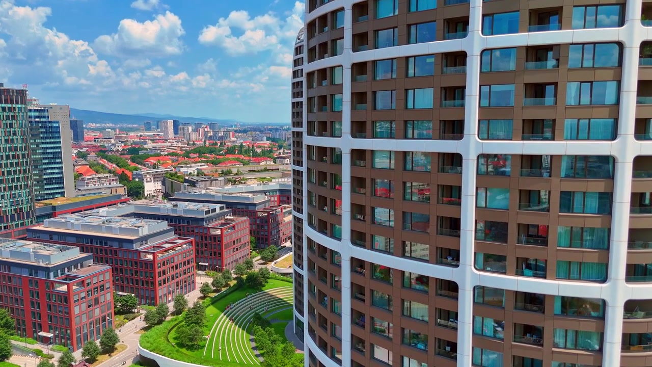 Bratislava, Eslovaquia, 2 de junio de 2026: Fachada de rascacielos cilíndrico alto con apartamentos residenciales, Bratislava, Eslovaquia. Torre moderna, ventanas de cristal, edificio de fábrica de ladrillo y parque urbano a la luz del día