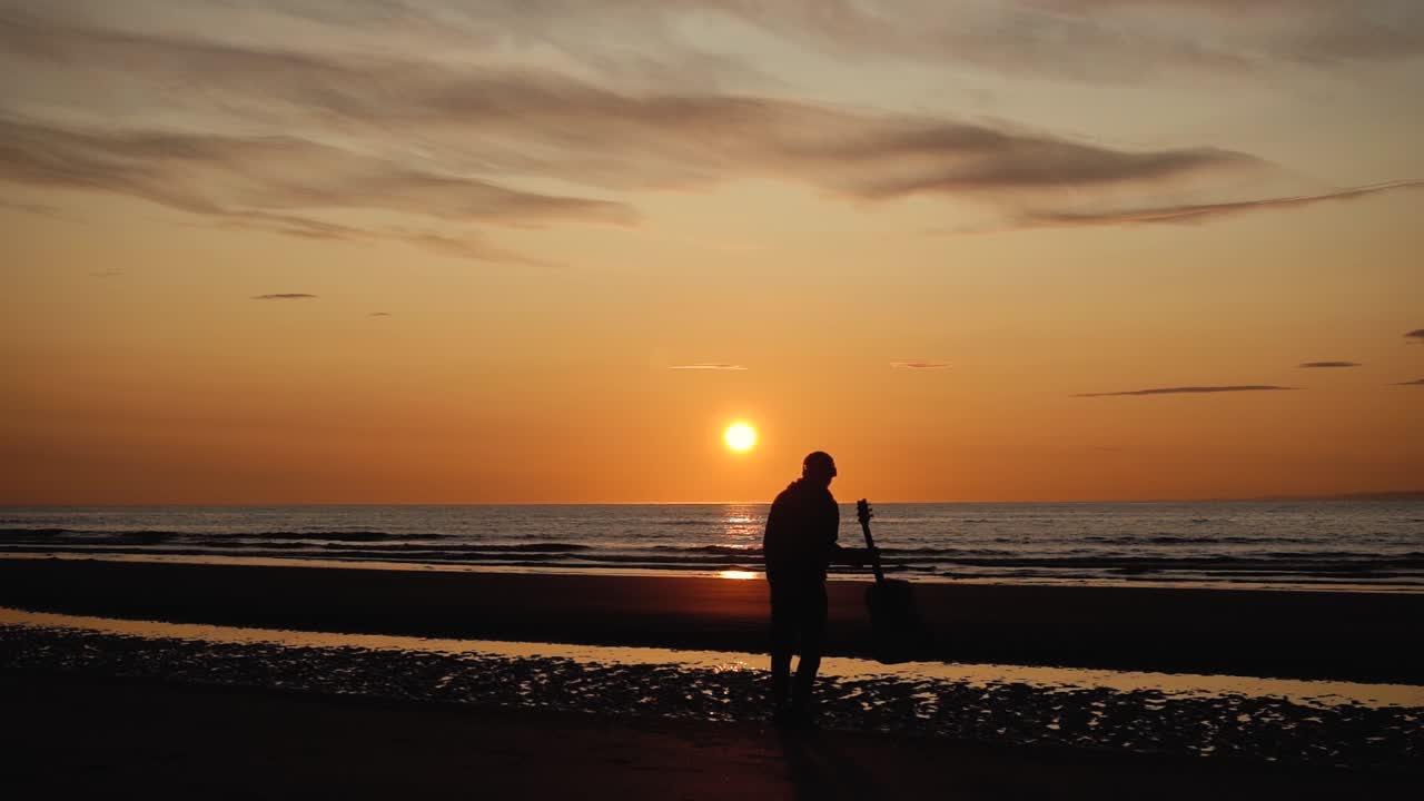 일몰-11에 뒷모래 해변에서 기타와 함께 달리는 남자
