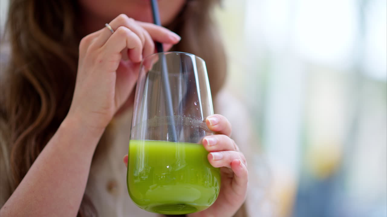 Woman drinking green matcha cocktail, at a cafe, outside