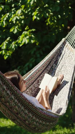 woman relaxing in a hammock, reading a book