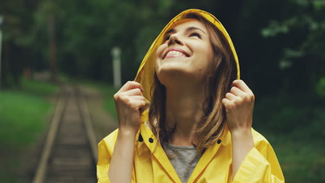 close up of a happy girl in a yellow raincoat smiling joyfully and looking up in the sky