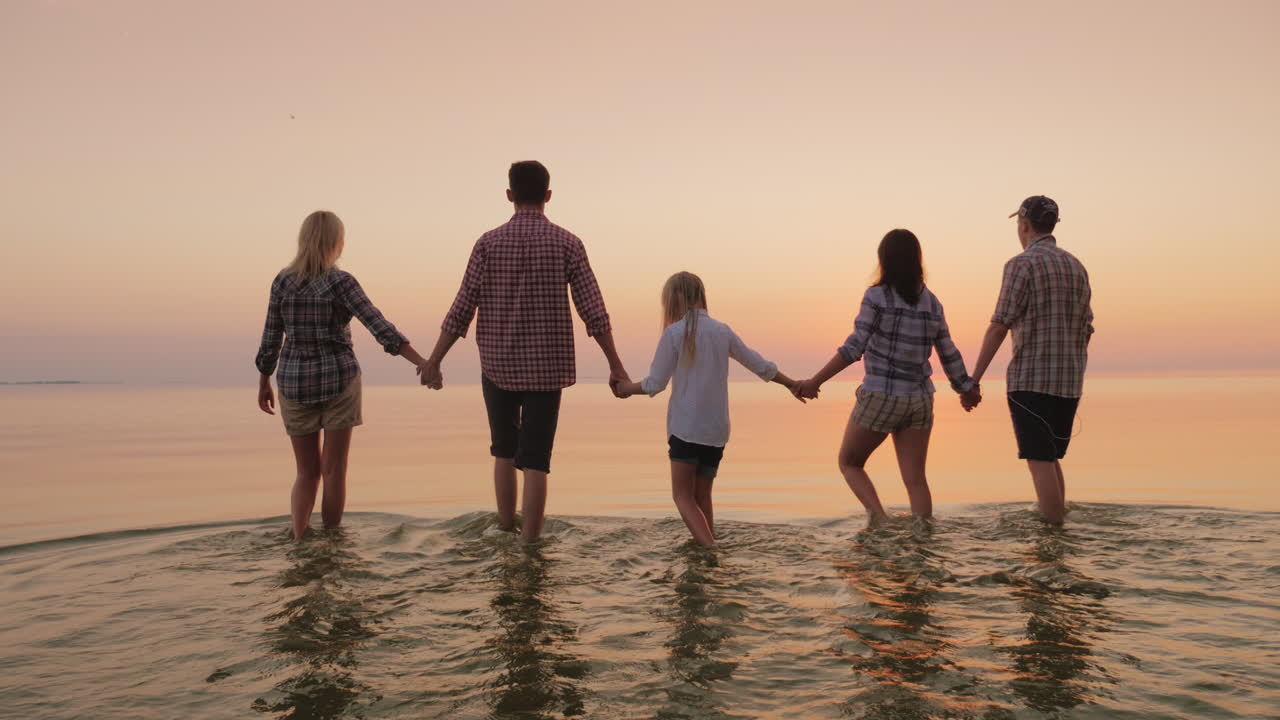 물 위를 걸어가는 손을 잡고 물가에서 즐거운 시간을 보내는 아이들과 함께 있는 친구들