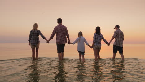 A-Group-Of-Friends-With-Children-Having-Fun-By-The-Water-Holding-Hands-Walking-On-The-Water-Towards-