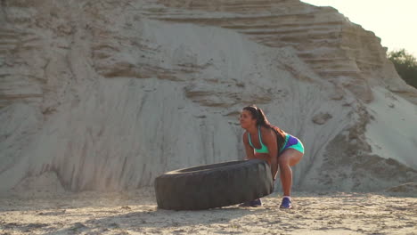 girl in sportswear pussh a tire. street workout.