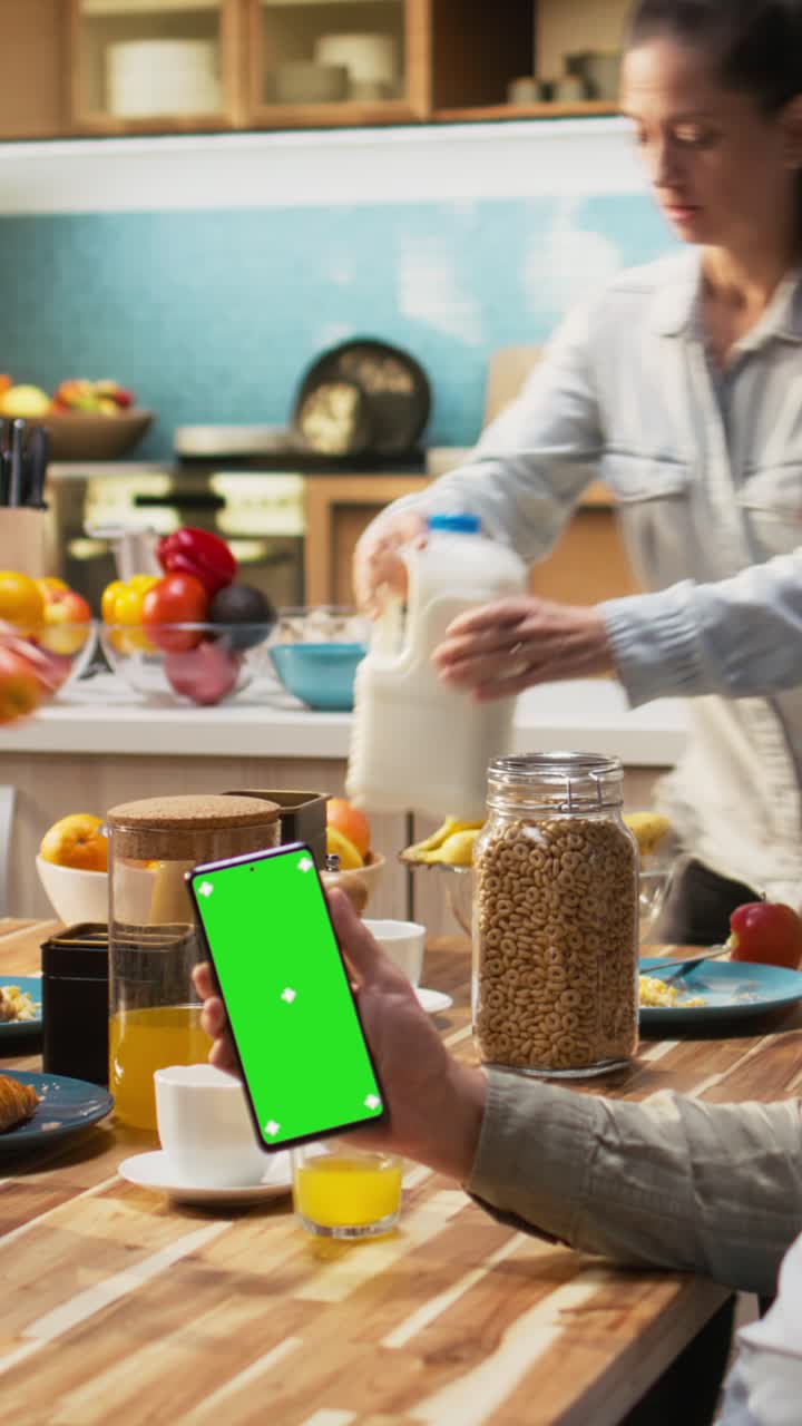 Vertical Video Vertical chroma key on phone next to family enjoying breakfast at the table