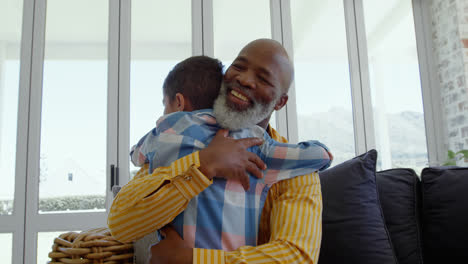 Front-view-of-mature-black-father-embracing-his-son-in-living-room-of-comfortable-home-4k