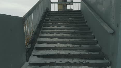 old grey stairs against frozen river covered with white snow