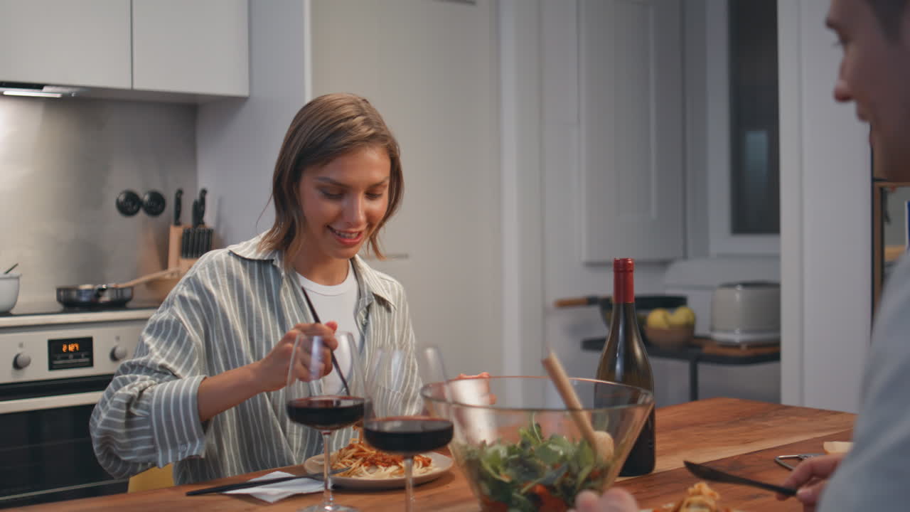 Married couple eating dinner in cozy kitchen. Smiling woman talking husband