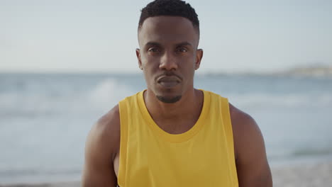 portrait-of-fit-handsome-african-american-man-looking-serious-at-camera-on-beach-wearing-yellow-vest