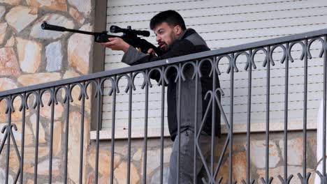 young man protects his home with an sniper rifle, aiming looking for intruders