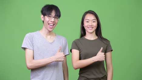 young asian couple giving thumbs up together