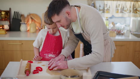 un niño y su padre hacen galletas de pan de jengibre