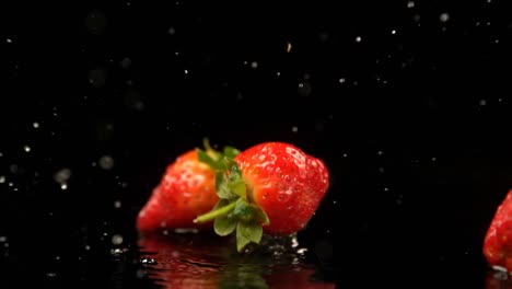 strawberries falling on water against black background 4k