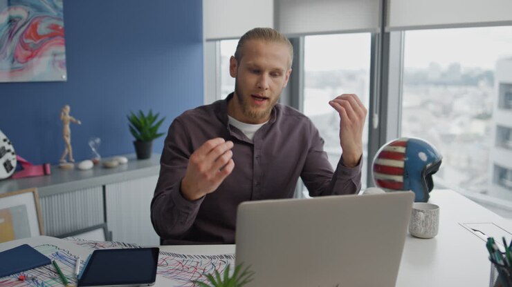 Annoyed guy screaming video call at workplace closeup. Angry man gesturing hands