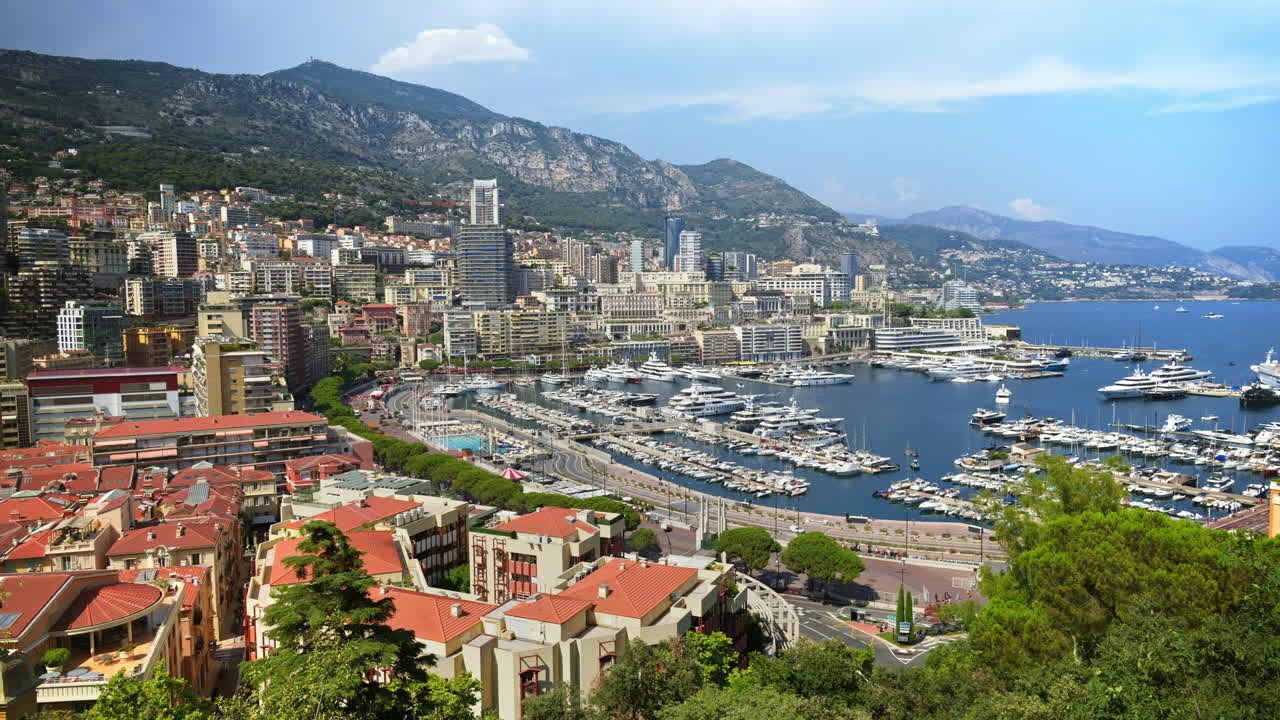 Vista aerea di barche bianche ormeggiate nel porto turistico di Monaco, con lo skyline sullo sfondo