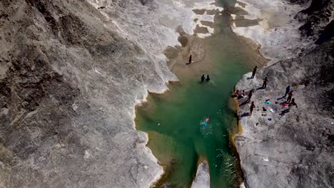 Kid-Boys-Spielen-Glücklich-In-Der-Natur,-Schwimmen-Fröhlich-In-Einem-Wunderschönen,-Klaren,-Grünen-Fluss-Aus-Wildwasser-In-Einem-Atemberaubenden-Bergtal-Im-Südiranischen-Naturbaluchistan-An-Einem-Sonnigen,-Angenehmen-Tag